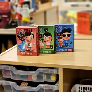 Colorful children's game boxes labeled 'Kids Box' on a store shelf with clear plastic bins underneath.